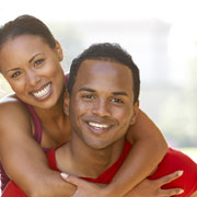 Woman hugging a man, both with big beautiful smiles. Both individuals are dressed in red, and is in a pose that is suggestive of being the recipients of a great dental inlay or onlay procedure.